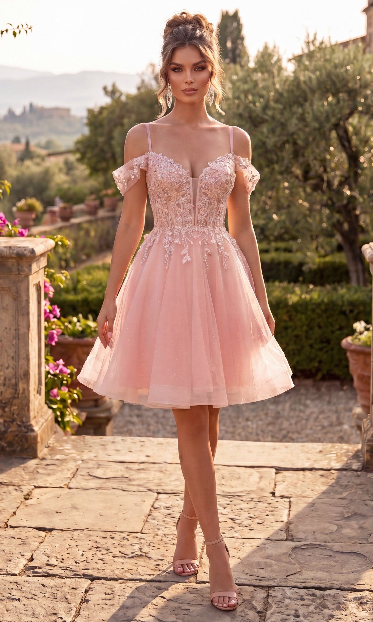 Wearing the blush Chicas C359 short homecoming dress, which features a corset bodice and delicate floral lace appliques, this woman pairs her look with strappy heels as she stands outdoors on a stone path in a garden setting.